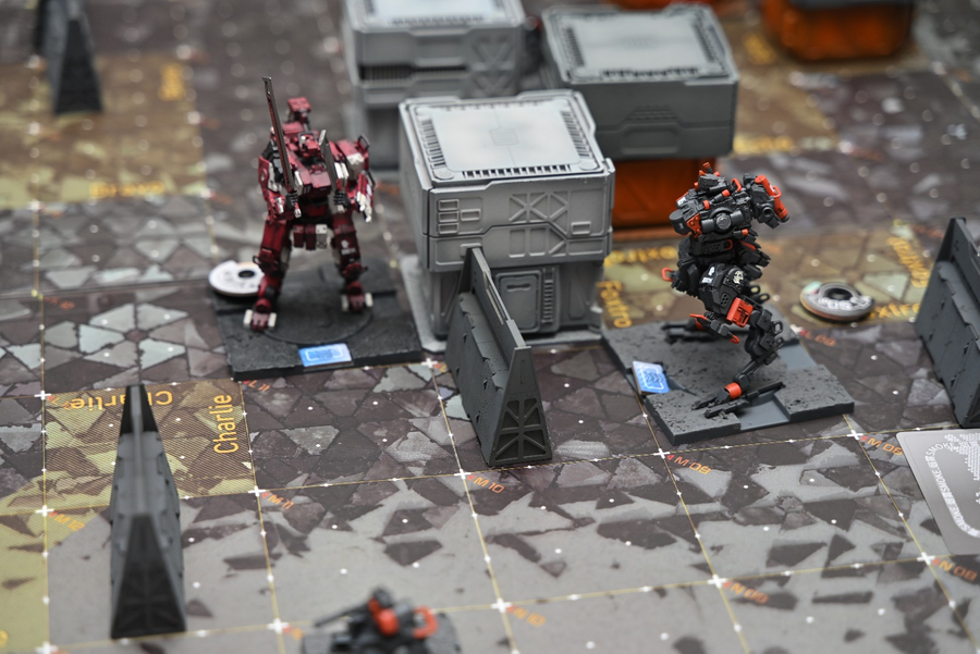 A photo of one game in EMBER: Obsidian Protocol, the mecha on the right is damaged and missing its arms.